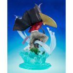 DOMA DEMON SLAYER: KIMETSU NO YAIBA FIGUARTS ZERO. En el brutal y místico universo de Demon Slayer: Kimetsu no Yaiba, Dôma destaca como una de las Doce Lunas Demoníacas más aterradoras, combinando elegancia, crueldad y fanatismo. Esta figura FiguartsZERO inmortaliza al demonio de rango superior Dos en una escena dinámica y escalofriante, fiel a su inquietante personalidad y a sus técnicas visualmente espectaculares. En plena invocación de sus técnicas de hielo, Dôma adopta una postura aérea y amenazante, con los brazos extendidos, blandiendo dos abanicos dorados decorados con motivos florales. Viste su icónico traje: una camiseta roja ajustada, mangas largas, pantalones holgados grises y una capa negra con bordes violetas en forma de cinta. Su sombrero triangular negro se mantiene firmemente sobre su cabello rubio, recogido en mechones revoloteantes. La base esculpida representa un efecto de hielo estilizado, que se eleva en remolinos translúcidos alrededor de su cuerpo, acentuado por flores de loto en plena floración. El efecto da la impresión de que Dôma baila sobre el agua, listo para lanzar un ataque mortal. El movimiento general de la escena es fluido, casi coreografiado, lo que refleja su naturaleza refinada y letal a la vez. Con una altura de 23 cm, esta figura de PVC impresiona por la delicadeza de sus detalles: texturas de tela, reflejos nacarados en los abanicos, transparencia trabajada en los elementos de hielo. La base es a la vez decorativa y funcional, lo que refuerza el impacto visual de la pose sin afectar a la estabilidad. Una pieza de colección memorable para los fans de la estética siniestra y estilizada de Demon Slayer.