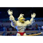 STUMP WRESTLING ACE DUCK TEENAGE MUTANT NINJA TURTLES ARCHIE COMICS. Ace Duck, personaje secundario de culto del universo Tortugas Ninja, reaparece aquí en su versión Stump Wrestling, inspirada en los famosos combates intergalácticos del multiverso TMNT. Este carismático luchador antropomórfico adopta aquí el aspecto de un guerrero samurái, listo para luchar en la arena con estilo y poderío. La figura representa a Ace Duck con un atuendo inspirado en el Japón feudal, con un kimono azul y negro, un cinturón rojo atado a la cintura y una espada enfundada. Su complexión robusta está perfectamente representada, con brazos musculosos, patas palmeadas y un feroz rostro de pato con colmillos visibles. Todo ello se acentúa con una capa de tela marrón y una variedad de accesorios evocadores. El conjunto incluye varias manos intercambiables, una antorcha esculpida, un escudo redondo y una gran capa flexible para variar las poses. Los detalles están cuidados al máximo: nervaduras en las alas, texturas del kimono, funda realista. La articulación fluida permite colocarlo en poses de combate o de parada. Con sus 18 cm, esta figura de NECA combina un guiño retro con una ejecución moderna. Una pieza ideal para los coleccionistas de la gama TMNT que quieran enriquecer su exposición con variantes originales y cuidadas.