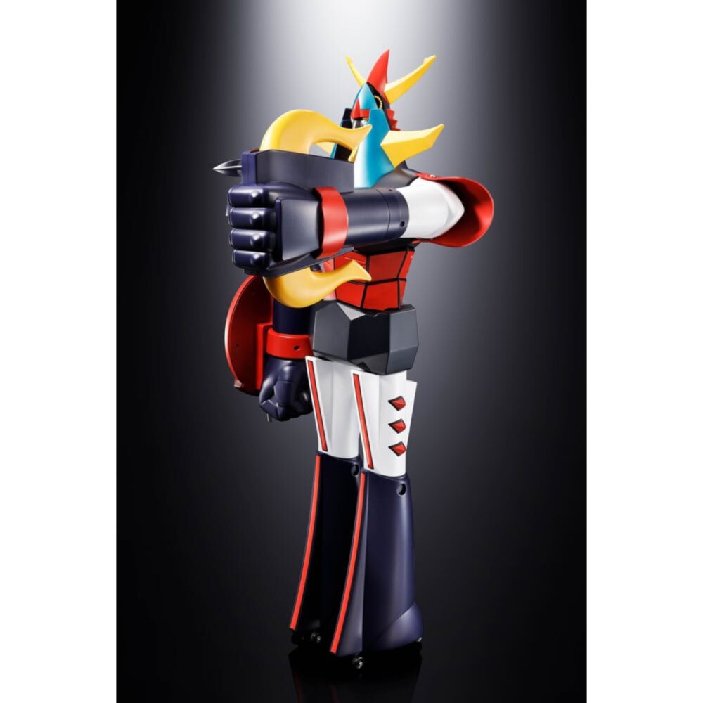 Raideen the brave jumbo machineder.  en el mítico universo de reideen the brave, el legendario robot despierta para defender la tierra de unos invasores procedentes de otra dimensión. Fusión de antiguas divinidades y tecnología futurista, reideen encarna un poder sagrado y protector, guiado por el joven héroe akira hibiki. La serie mezcla misticismo, acción y drama, en un ambiente marcado por el peso del destino. Esta versión jumbo machinder rinde homenaje a la estética vintage del mecha de culto. Reideen se presenta aquí en una postura frontal, imponente, casi totémica. La silueta rígida y maciza refuerza su carácter inquebrantable, verdadero baluarte frente a las fuerzas del mal. El diseño es un éxito de fidelidad: casco azul adornado con cuernos dorados, torso rojo en segmentos geométricos, antebrazos poderosos rematados por un escudo redondo y un puño lanzador de picas. Las piernas largas, nervadas en rojo y negro, alargan la estatura, acentuando la dimensión heroica. La pintura mate, los bordes definidos y el juego de volúmenes dan un resultado escultural sorprendente. Con sus 60 cm de altura, esta impresionante pieza está fabricada por bandai tamashii nations siguiendo el espíritu de las figuras vintage jumbo. Sólida, estable y visualmente espectacular, constituye por sí sola el centro de cualquier colección. Perfecta para los amantes de los robots clásicos y el diseño retro.