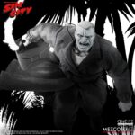 MARV SIN CITY ONE:12 COLLECTIVE. Mezco Toyz presenta dentro de su línea One:12 Collective la figura articulada de Marv, inspirada en la apariencia del personaje de la icónica obra de Frank Miller "Sin City". Esta imponente figura tiene una altura aproximada de 17 cm y refleja a la perfección el estilo crudo y violento del antihéroe más brutal de Basin City. Cuenta con más de 30 puntos de articulación y viene acompañada de 3x placas faciales, 9x manos adicionales, 1x pistola Gladys con 2x cargadores extraíbles, 2x efectos de disparo, 1x sierra, 1x hacha, 1x bidón de gasolina con 1x efecto de llama extraíble, 1x mechero encendido, 1x paquete de cigarrillos abierto, 3x cigarrillos encendidos, 1x par de esposas y 1x cabeza decapitada de Kevin con mechón desmontable que permite sujetarla. Su atuendo incluye un abrigo largo envejecido, camiseta, pantalones, botas y un colgante con cruz. Se presenta en una caja con detalles gráficos inspirados en la obra original.
