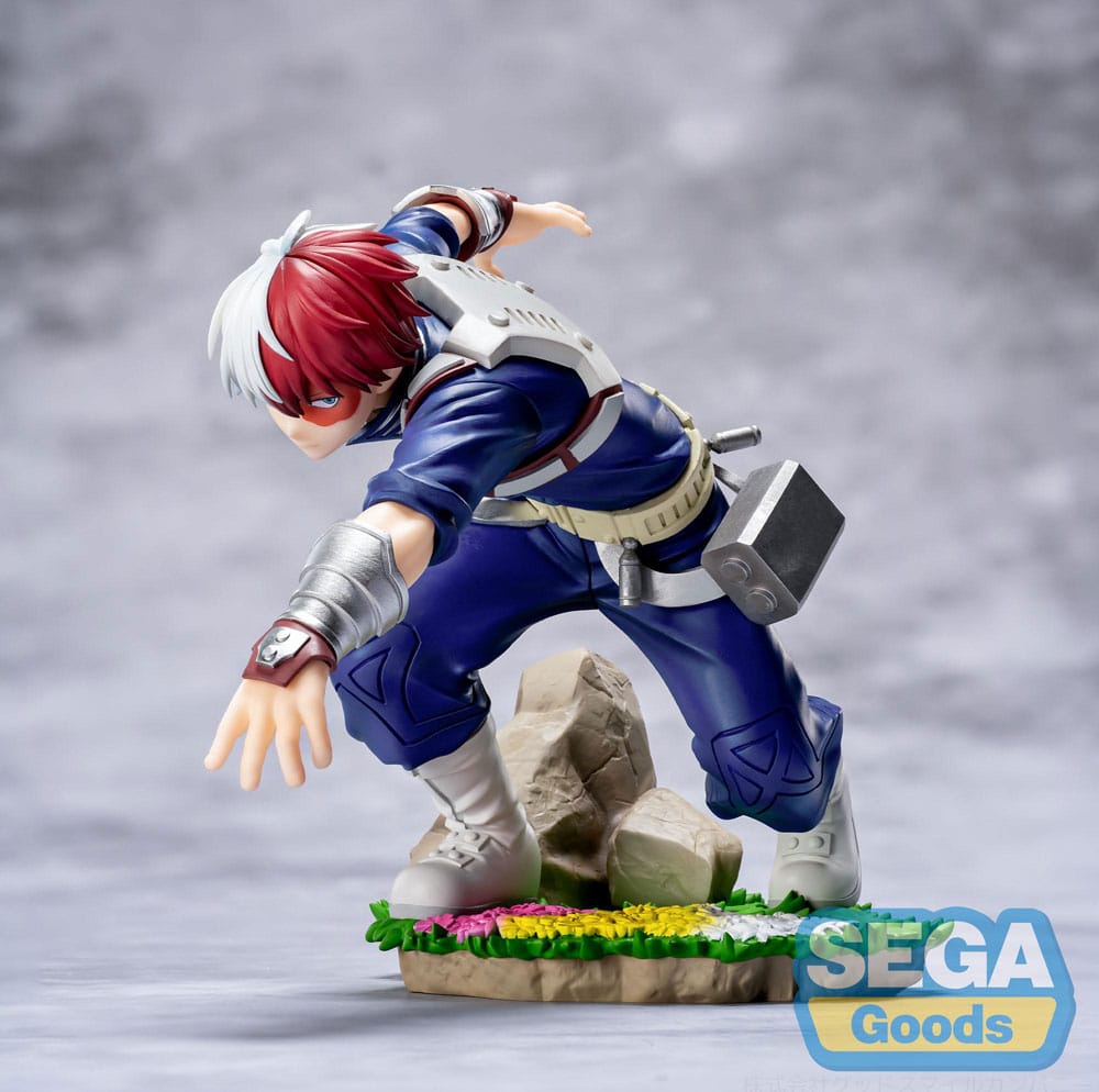 SHOTO TODOROKI MY HERO ACADEMIA: YOU´RE NEXT XROSS LINK ANIME. En My Hero Academia: La película, Shoto Todoroki sigue creciendo mientras domina dos fuerzas opuestas: el hielo y el fuego. Como heredero de un complejo legado familiar y un inmenso poder, representa el equilibrio entre el control y la fuerza bruta, avanzando constantemente hacia su propia visión del heroísmo. Esta figura de la colección Xross Link lo captura en plena acción, en una postura de combate serena. Con una rodilla doblada, el brazo extendido y la mirada fija al frente, cada detalle transmite su concentración y su calma estratégica. La escultura se mantiene fiel a su aspecto: traje de héroe azul oscuro con cinturón utilitario y protectores metálicos para los brazos, junto con un cabello rojo y blanco perfectamente representado. La base presenta rocas, hierba y flores, lo que resalta el contraste entre su postura tensa y el terreno tranquilo. Con una altura aproximada de 12 cm, esta figura de PVC presenta proporciones limpias y detalles nítidos. Los pliegues del traje, los sutiles degradados del pelo y los accesorios texturizados están elaborados con precisión, lo que ofrece una representación fiel de la doble naturaleza de Todoroki.