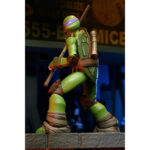 ULTIMATE DONATELLO TEENAGE MUTANT NINJA TURTLES (2012). En la serie animada Teenage Mutant Ninja Turtles de 2012, Donatello es el cerebro técnico del equipo. Aborda cada situación con precisión, equilibrando inventos, improvisación y un profundo sentido de la responsabilidad. Su mentalidad tranquila y lógica mantiene al grupo con los pies en la tierra mientras sus hermanos se lanzan al ataque. A lo largo de la serie, Donnie es a menudo quien idea soluciones cuando las cosas se complican. Ya sea construyendo nuevos equipos, analizando amenazas u ofreciendo un apoyo silencioso, se erige como la fuerza estabilizadora y el solucionador de problemas del equipo. La figura captura con precisión su aspecto de 2012: caparazón beige y marrón, piel verde, máscara morada y almohadillas de armadura marrones. Su expresión neutra se complementa con una cara alternativa más expresiva. El conjunto de accesorios es muy completo e incluye bastones segmentados, artilugios, manos intercambiables, visera tecnológica, porción de pizza, huevo, pieza de armadura e incluso un pollo mutante sacado directamente de la serie. El esculpido nítido, la aplicación limpia de la pintura y las articulaciones bien integradas realzan la presencia de la figura. Con 18 cm de altura, ofrece una articulación sólida para posar de forma dinámica y recrear escenas de la serie.
