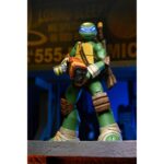 ULTIMATE LEONARDO TEENAGE MUTANT NINJA TURTLES (2012). En la serie animada Teenage Mutant Ninja Turtles de 2012, Leonardo encarna la figura del líder tranquilo y decidido. Siempre preocupado por hacer lo correcto, guía a sus hermanos con una mezcla de responsabilidad, disciplina y dudas que poco a poco aprende a superar. Su trayectoria muestra a un luchador que se esfuerza por progresar tanto en su técnica como en su papel de líder. Entre decisiones difíciles, entrenamientos intensos y momentos más ligeros con su equipo, Leo sigue siendo el punto de equilibrio que mantiene unido al grupo. La figura reproduce con precisión su diseño de 2012: caparazón beige y marrón, piel verde, máscara azul y protecciones marrones en las extremidades. Su expresión neutra puede sustituirse por una cabeza alternativa más dinámica. Los accesorios incluyen sus dos katanas, manos intercambiables, una porción de pizza, un trozo de armadura y un bláster fiel al estilo de la serie. Los detalles son nítidos: segmentos esculpidos del caparazón, pintura limpia, articulaciones bien integradas y accesorios correctamente proporcionados. Con sus 18 cm, la figura permite numerosas poses emblemáticas del personaje.