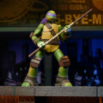 ULTIMATE DONATELLO TEENAGE MUTANT NINJA TURTLES (2012). En la serie animada Teenage Mutant Ninja Turtles de 2012, Donatello es el cerebro técnico del equipo. Aborda cada situación con precisión, equilibrando inventos, improvisación y un profundo sentido de la responsabilidad. Su mentalidad tranquila y lógica mantiene al grupo con los pies en la tierra mientras sus hermanos se lanzan al ataque. A lo largo de la serie, Donnie es a menudo quien idea soluciones cuando las cosas se complican. Ya sea construyendo nuevos equipos, analizando amenazas u ofreciendo un apoyo silencioso, se erige como la fuerza estabilizadora y el solucionador de problemas del equipo. La figura captura con precisión su aspecto de 2012: caparazón beige y marrón, piel verde, máscara morada y almohadillas de armadura marrones. Su expresión neutra se complementa con una cara alternativa más expresiva. El conjunto de accesorios es muy completo e incluye bastones segmentados, artilugios, manos intercambiables, visera tecnológica, porción de pizza, huevo, pieza de armadura e incluso un pollo mutante sacado directamente de la serie. El esculpido nítido, la aplicación limpia de la pintura y las articulaciones bien integradas realzan la presencia de la figura. Con 18 cm de altura, ofrece una articulación sólida para posar de forma dinámica y recrear escenas de la serie.