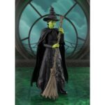 ELPHABA WICKED SH FIGUARTS. Inspirada en el musical de culto Wicked, esta figura captura toda la misteriosa intensidad de Elphaba, la bruja con un destino adverso. En un mundo en el que la apariencia y la verdad se enfrentan, ella se enfrenta con orgullo a los prejuicios y las manipulaciones, barriendo las convenciones con un simple hechizo. Heroína atípica y conmovedora, Elphaba encarna una resistencia interior marcada por la injusticia. Lejos de la imagen tradicional de la bruja malvada, a lo largo de la historia revela una complejidad poco común y conmovedora, lo que la convierte en uno de los personajes más fuertes y humanos de la narración. La figura la muestra de espaldas, en una postura llena de dignidad, ligeramente girada, con una escoba en la mano. Su piel verde resalta bajo la luz del atardecer, contrastando con su largo vestido negro texturizado, su sombrero puntiagudo torcido y su cabello trenzado. Cada pliegue de la tela, cada detalle del accesorio evoca un trabajo minucioso fiel al universo de la escena. Con unos 14 cm de altura, esta figura articulada de PVC pertenece a la colección S.H. Figuarts de Bandai. La delicada escultura, los efectos de textura del vestido, el realismo de la escoba y las elegantes proporciones la convierten en una pieza expresiva, perfecta para recrear escenas emblemáticas del musical.
