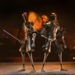 ULTIMATE FOOT SOLDIER TEENAGE MUTANT NINJA TURTLES (2012). En la serie animada Teenage Mutant Ninja Turtles de 2012, los soldados Foot representan la amenaza silenciosa y persistente del clan Foot. Siempre presentes en las sombras, operan en grupos, siguen órdenes sin dudar y empujan constantemente a las Tortugas hasta sus límites. Su papel enfatiza la estricta disciplina del clan. Ya sea en emboscadas, persecuciones o batallas coordinadas, los soldados Foot siguen siendo oponentes implacables que aumentan la tensión de cada encuentro. La figura recrea su aspecto alto y esbelto: traje negro, extremidades angulosas, máscara oscura con ojos rojos y la característica cinta roja en la cabeza. El set incluye una amplia gama de armas, como guadañas, una maza con púas, una lanza, una katana y otros accesorios fieles a la serie. Las múltiples manos intercambiables y una cabeza alternativa ofrecen una gran flexibilidad a la hora de colocar la figura. Los detalles nítidos destacan en las texturas del traje, las proporciones estilizadas, la pintura limpia y los accesorios bien elaborados. Con 18 cm de altura, la figura ofrece una articulación sólida para poses sigilosas o centradas en la acción inspiradas en los dibujos animados.