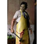 LEATHERFACE CLOTHED THE TEXAS CHAINSAW MASSACRE. En La matanza de Texas, Leatherface provoca una sensación inmediata de terror. Callado, impredecible y siempre oculto tras su máscara, encarna el peligro en estado puro y contribuye a crear la atmósfera opresiva de la película. Su papel sigue la trayectoria de un personaje aterrador e inolvidable. Atrapado en una familia desquiciada e impulsado por impulsos violentos, Leatherface ataca sin una lógica clara, lo que hace que cada una de sus apariciones resulte aún más inquietante. La figura refleja su aspecto característico: máscara cosida, camisa a rayas claras, corbata oscura y un gran delantal amarillo marcado con manchas rojas. Su despeinado cabello negro, sus pantalones oscuros y sus zapatos resistentes están fielmente recreados. Las imágenes muestran múltiples accesorios, incluyendo un martillo y una motosierra. La ropa de tela típica de la línea Clothed de NECA añade realismo. Los detalles nítidos destacan en la textura del delantal, la escultura de la máscara, los pliegues de la ropa y los accesorios de buen tamaño. Con una altura de 20 cm, la figura tiene una sólida presencia en la estantería y se puede colocar con diferentes accesorios.