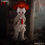 PENNYWISE IT LIVING DEAD DOLLS. Directamente del aterrador mundo de It, la historia de terror de culto de Stephen King, esta muñeca representa la encarnación moderna del payaso Pennywise tal y como aparece en las adaptaciones cinematográficas de 2017 y 2019. Pennywise, una figura inquietante que reaparece en Derry cada 27 años, encarna el miedo en sí mismo y atrae a sus víctimas con su aspecto infantil y payaso. Con una sonrisa siniestra y un globo rojo en la mano, esta miniatura de Pennywise captura la inquietante mezcla de alegría juguetona y amenaza acechante. Con sus mangas abullonadas, su traje de payaso envejecido, sus pompones rojos y su mirada penetrante, esta muñeca ofrece una escalofriante representación del horror en su forma más engañosa. Su pálido rostro está enmarcado por un cabello salvaje y naranja vibrante, esculpido para imitar el aspecto icónico del personaje. Las nítidas marcas rojas de su rostro resaltan su siniestra sonrisa, mientras que el traje de tela real, con volantes y costuras rojas, añade profundidad y una inquietante autenticidad a la figura. Con una altura aproximada de 25 cm, esta muñeca forma parte de la colección Living Dead Dolls de Mezco Toys. Con su inquietante mirada, su globo rojo desmontable y su presencia inquietante, es una pieza imprescindible para los amantes del terror o los coleccionistas de lo deliciosamente macabro.
