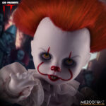 PENNYWISE IT LIVING DEAD DOLLS. Directamente del aterrador mundo de It, la historia de terror de culto de Stephen King, esta muñeca representa la encarnación moderna del payaso Pennywise tal y como aparece en las adaptaciones cinematográficas de 2017 y 2019. Pennywise, una figura inquietante que reaparece en Derry cada 27 años, encarna el miedo en sí mismo y atrae a sus víctimas con su aspecto infantil y payaso. Con una sonrisa siniestra y un globo rojo en la mano, esta miniatura de Pennywise captura la inquietante mezcla de alegría juguetona y amenaza acechante. Con sus mangas abullonadas, su traje de payaso envejecido, sus pompones rojos y su mirada penetrante, esta muñeca ofrece una escalofriante representación del horror en su forma más engañosa. Su pálido rostro está enmarcado por un cabello salvaje y naranja vibrante, esculpido para imitar el aspecto icónico del personaje. Las nítidas marcas rojas de su rostro resaltan su siniestra sonrisa, mientras que el traje de tela real, con volantes y costuras rojas, añade profundidad y una inquietante autenticidad a la figura. Con una altura aproximada de 25 cm, esta muñeca forma parte de la colección Living Dead Dolls de Mezco Toys. Con su inquietante mirada, su globo rojo desmontable y su presencia inquietante, es una pieza imprescindible para los amantes del terror o los coleccionistas de lo deliciosamente macabro.