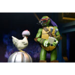 ULTIMATE DONATELLO TEENAGE MUTANT NINJA TURTLES (2012). En la serie animada Teenage Mutant Ninja Turtles de 2012, Donatello es el cerebro técnico del equipo. Aborda cada situación con precisión, equilibrando inventos, improvisación y un profundo sentido de la responsabilidad. Su mentalidad tranquila y lógica mantiene al grupo con los pies en la tierra mientras sus hermanos se lanzan al ataque. A lo largo de la serie, Donnie es a menudo quien idea soluciones cuando las cosas se complican. Ya sea construyendo nuevos equipos, analizando amenazas u ofreciendo un apoyo silencioso, se erige como la fuerza estabilizadora y el solucionador de problemas del equipo. La figura captura con precisión su aspecto de 2012: caparazón beige y marrón, piel verde, máscara morada y almohadillas de armadura marrones. Su expresión neutra se complementa con una cara alternativa más expresiva. El conjunto de accesorios es muy completo e incluye bastones segmentados, artilugios, manos intercambiables, visera tecnológica, porción de pizza, huevo, pieza de armadura e incluso un pollo mutante sacado directamente de la serie. El esculpido nítido, la aplicación limpia de la pintura y las articulaciones bien integradas realzan la presencia de la figura. Con 18 cm de altura, ofrece una articulación sólida para posar de forma dinámica y recrear escenas de la serie.