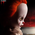 PENNYWISE IT LIVING DEAD DOLLS. Directamente del aterrador mundo de It, la historia de terror de culto de Stephen King, esta muñeca representa la encarnación moderna del payaso Pennywise tal y como aparece en las adaptaciones cinematográficas de 2017 y 2019. Pennywise, una figura inquietante que reaparece en Derry cada 27 años, encarna el miedo en sí mismo y atrae a sus víctimas con su aspecto infantil y payaso. Con una sonrisa siniestra y un globo rojo en la mano, esta miniatura de Pennywise captura la inquietante mezcla de alegría juguetona y amenaza acechante. Con sus mangas abullonadas, su traje de payaso envejecido, sus pompones rojos y su mirada penetrante, esta muñeca ofrece una escalofriante representación del horror en su forma más engañosa. Su pálido rostro está enmarcado por un cabello salvaje y naranja vibrante, esculpido para imitar el aspecto icónico del personaje. Las nítidas marcas rojas de su rostro resaltan su siniestra sonrisa, mientras que el traje de tela real, con volantes y costuras rojas, añade profundidad y una inquietante autenticidad a la figura. Con una altura aproximada de 25 cm, esta muñeca forma parte de la colección Living Dead Dolls de Mezco Toys. Con su inquietante mirada, su globo rojo desmontable y su presencia inquietante, es una pieza imprescindible para los amantes del terror o los coleccionistas de lo deliciosamente macabro.