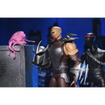 ULTIMATE SHREDDER TEENAGE MUTANT NINJA TURTLES (2012). En la serie animada Teenage Mutant Ninja Turtles de 2012, Shredder es el enemigo más formidable de las Tortugas Ninja. Su presencia eleva instantáneamente el nivel de tensión. Calculador, despiadado e impulsado por la venganza, marca la tensión de la serie cada vez que aparece en escena. A lo largo de la serie, Shredder actúa como un estratega implacable cuyo objetivo es destruir a Splinter y a sus alumnos. Su obsesión alimenta algunas de las batallas más intensas de la serie. A través de la manipulación, los duelos brutales y las alianzas inestables, sigue siendo una fuerza imparable. La figura captura con precisión su aspecto de 2012: armadura angular plateada, guanteletes con largas espadas, grebas pesadas y un casco con cuernos afilados. Una capa negra realza su imponente silueta. Los accesorios incluyen múltiples espadas intercambiables, manos adicionales, una cabeza alternativa sin máscara y una criatura Krang rosa sacada directamente de los dibujos animados. Los detalles nítidos resaltan la armadura metálica, el esculpido limpio, las articulaciones discretas y los accesorios a escala. Con 18 cm de altura, la figura ofrece una articulación sólida, perfecta para recrear los momentos icónicos de Shredder.